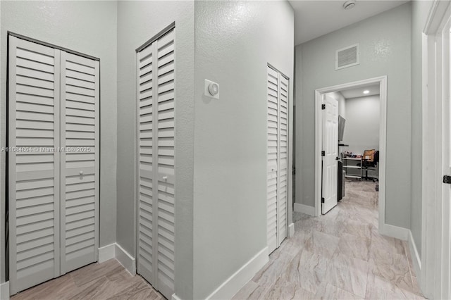 corridor with marble finish floor, visible vents, and baseboards