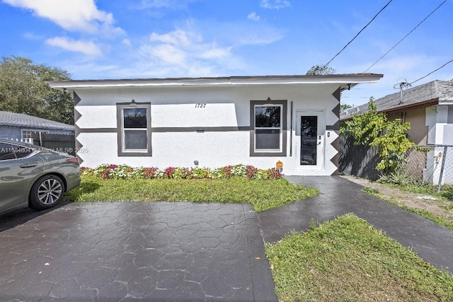 bungalow-style home with fence and stucco siding