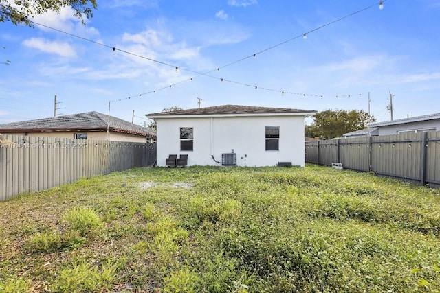 rear view of house featuring a yard, a fenced backyard, cooling unit, and stucco siding