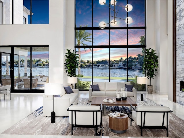 living room featuring a towering ceiling, a healthy amount of sunlight, and a water view