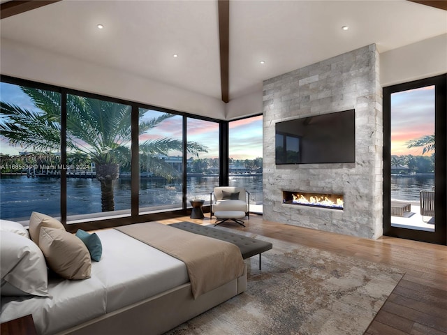 bedroom featuring multiple windows, wood-type flooring, and a fireplace