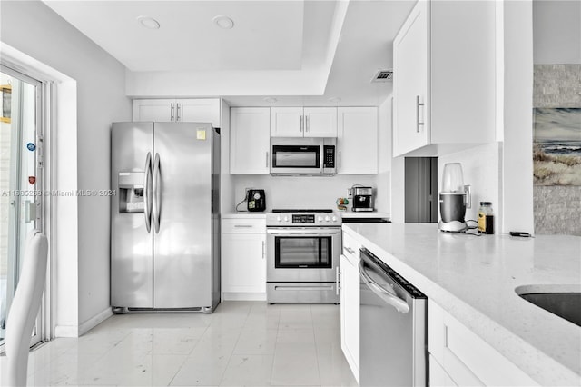 kitchen featuring light stone countertops, white cabinets, and stainless steel appliances