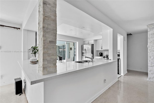 kitchen with kitchen peninsula, white cabinets, sink, and stainless steel fridge with ice dispenser