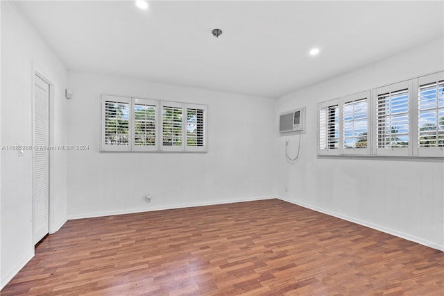 spare room featuring an AC wall unit and wood-type flooring