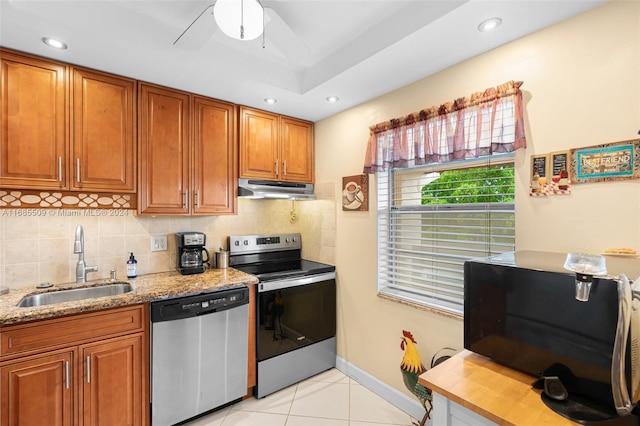 kitchen with decorative backsplash, appliances with stainless steel finishes, light stone countertops, sink, and light tile patterned floors