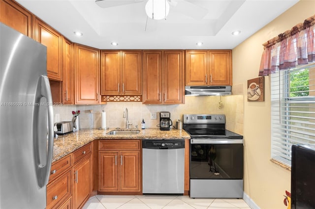 kitchen featuring light stone countertops, appliances with stainless steel finishes, backsplash, sink, and light tile patterned floors