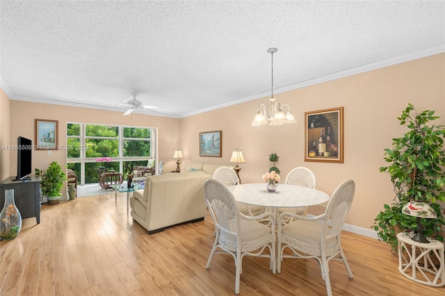 dining area with ceiling fan with notable chandelier, a textured ceiling, light wood-type flooring, and crown molding