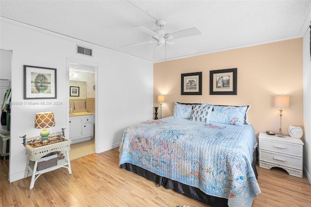 bedroom with ceiling fan, ensuite bathroom, light hardwood / wood-style floors, and a textured ceiling