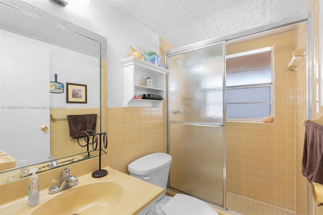 bathroom with vanity, an enclosed shower, tile walls, and toilet