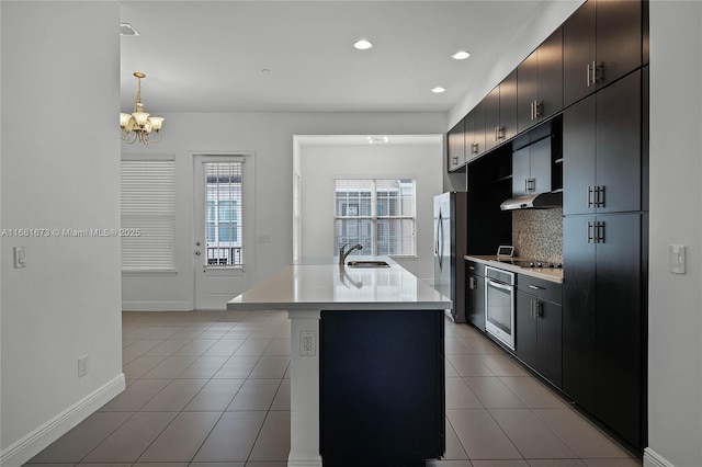 kitchen with pendant lighting, sink, stainless steel appliances, an island with sink, and light tile patterned flooring