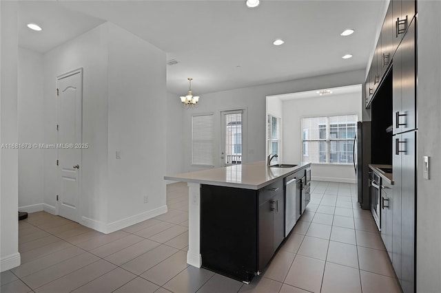 kitchen featuring sink, hanging light fixtures, a kitchen island with sink, light tile patterned floors, and stainless steel appliances