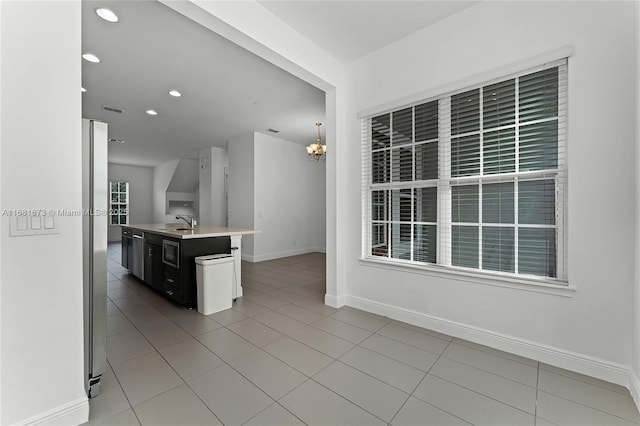 kitchen with an island with sink, pendant lighting, sink, and light tile patterned floors