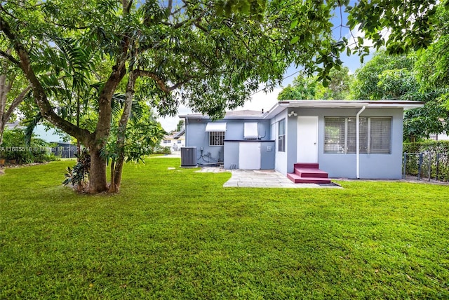 rear view of house featuring a yard and central AC