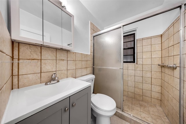 bathroom featuring vanity, toilet, tile walls, and a shower with shower door