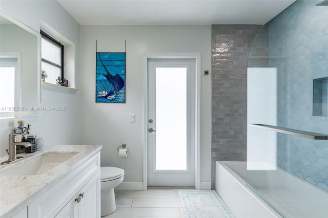 full bathroom with tiled shower / bath, vanity, toilet, and a wealth of natural light