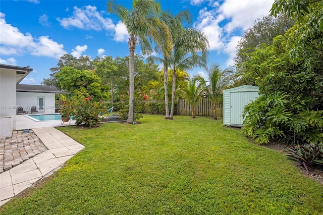 view of yard featuring a patio, a fenced in pool, and a shed