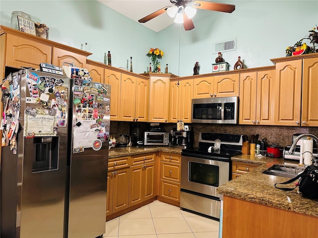 kitchen featuring appliances with stainless steel finishes, dark stone counters, decorative backsplash, sink, and light tile patterned flooring