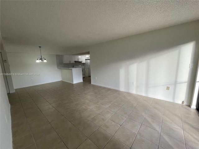 unfurnished living room with tile patterned flooring, a textured ceiling, and an inviting chandelier