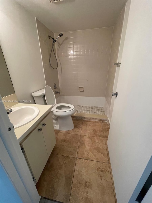 bathroom with tiled shower, tile patterned floors, vanity, and toilet