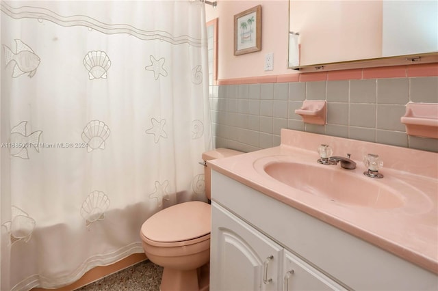 bathroom featuring vanity, toilet, and tile walls