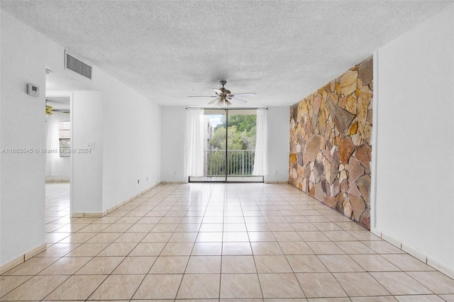 tiled empty room with ceiling fan and a textured ceiling