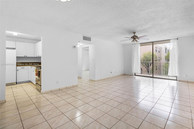 unfurnished living room with a textured ceiling, light tile patterned floors, and ceiling fan