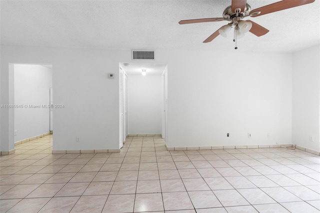 tiled spare room with a textured ceiling and ceiling fan