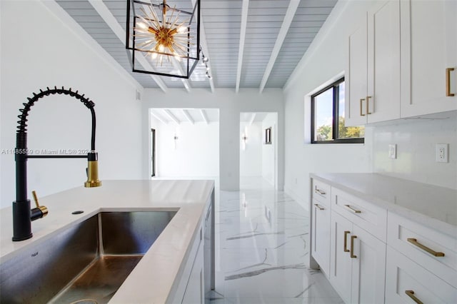 kitchen featuring vaulted ceiling with beams, hanging light fixtures, sink, white cabinets, and light stone counters