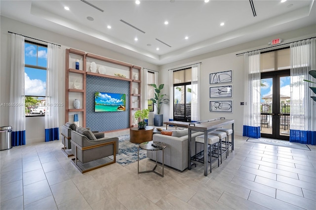 living room featuring a raised ceiling, french doors, and light tile patterned flooring