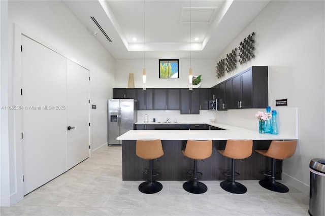 kitchen featuring a tray ceiling, kitchen peninsula, a breakfast bar, and stainless steel appliances