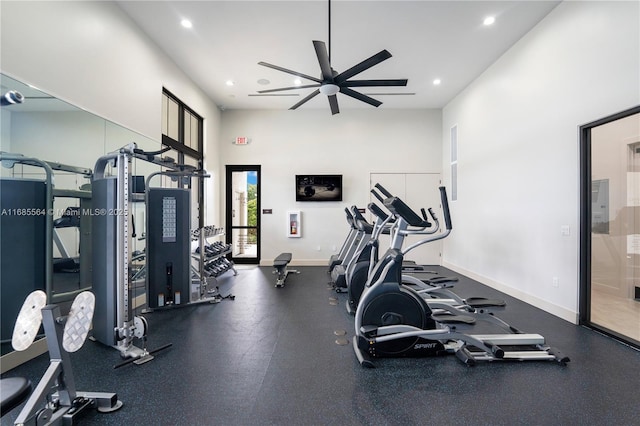 exercise room with ceiling fan and a high ceiling