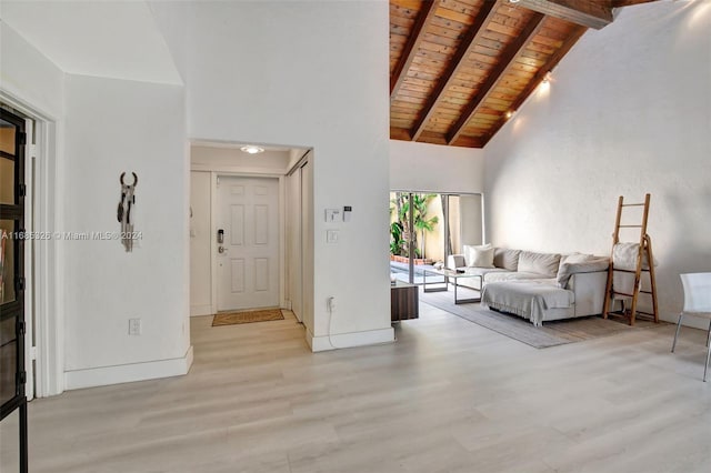 living room featuring light hardwood / wood-style floors, high vaulted ceiling, beamed ceiling, and wooden ceiling