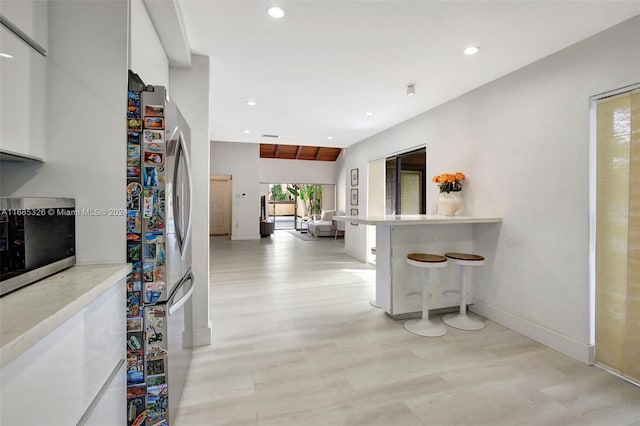 hall featuring light wood-type flooring and vaulted ceiling