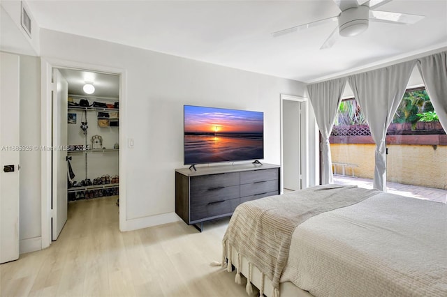 bedroom featuring a closet, ceiling fan, a spacious closet, and light hardwood / wood-style flooring