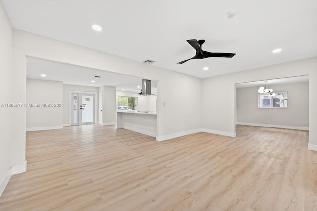 unfurnished living room with french doors, light wood-type flooring, and ceiling fan with notable chandelier