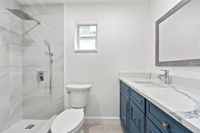 bathroom featuring toilet, vanity, a tile shower, and wood-type flooring