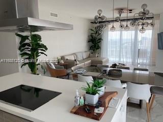 interior space featuring black electric stovetop, white cabinets, and ventilation hood