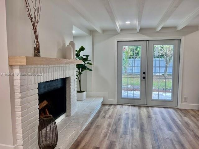 doorway featuring hardwood / wood-style floors, beam ceiling, a brick fireplace, and french doors