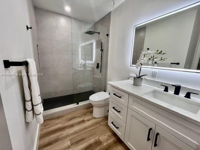 bathroom featuring a tile shower, toilet, vanity, and hardwood / wood-style flooring