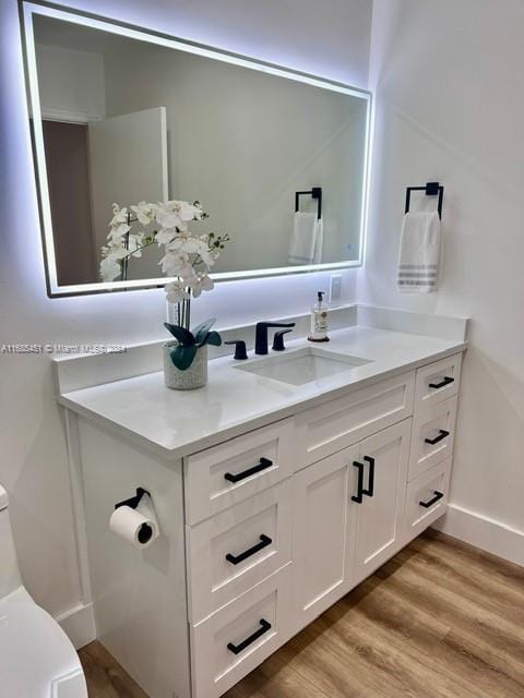 bathroom with hardwood / wood-style flooring, vanity, and toilet