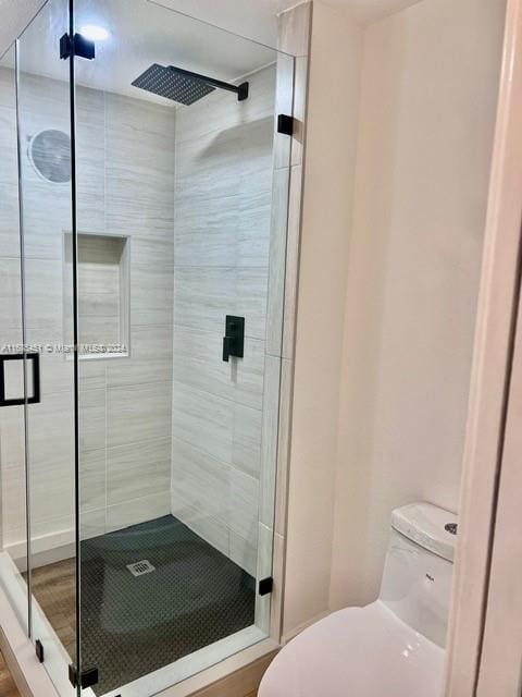 bathroom with toilet and a shower with shower door