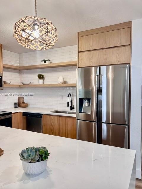 kitchen with light stone countertops, backsplash, stainless steel appliances, sink, and pendant lighting