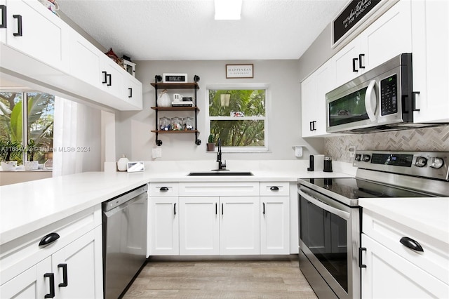 kitchen featuring appliances with stainless steel finishes, white cabinetry, sink, and light wood-type flooring