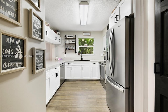 kitchen featuring white cabinetry, a textured ceiling, light hardwood / wood-style flooring, sink, and stainless steel appliances