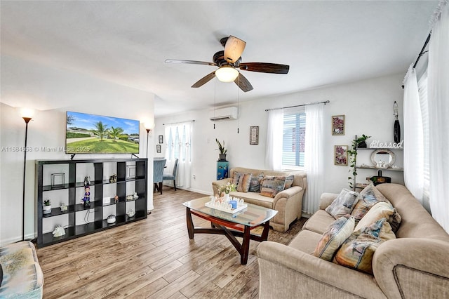 living room featuring ceiling fan, a wall unit AC, and light hardwood / wood-style flooring