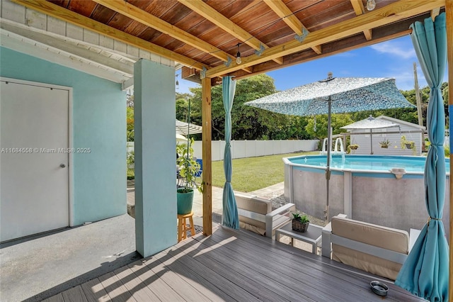 wooden deck with a fenced in pool, a patio, and a yard