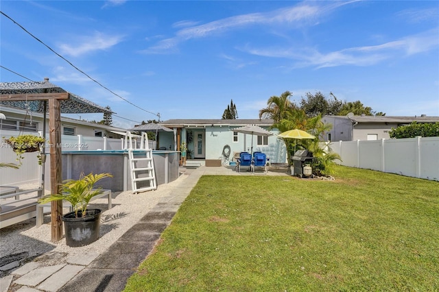 rear view of property with a fenced in pool, a yard, and a patio area