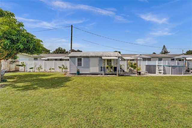 back of property featuring an outbuilding, a fenced in pool, a pergola, and a lawn