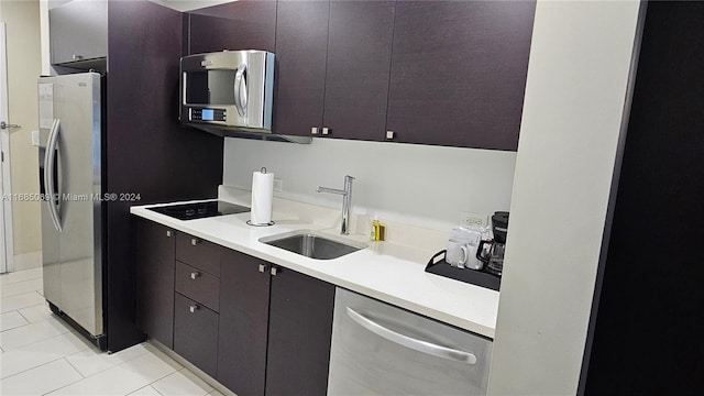 kitchen featuring appliances with stainless steel finishes, light tile patterned flooring, dark brown cabinetry, and sink