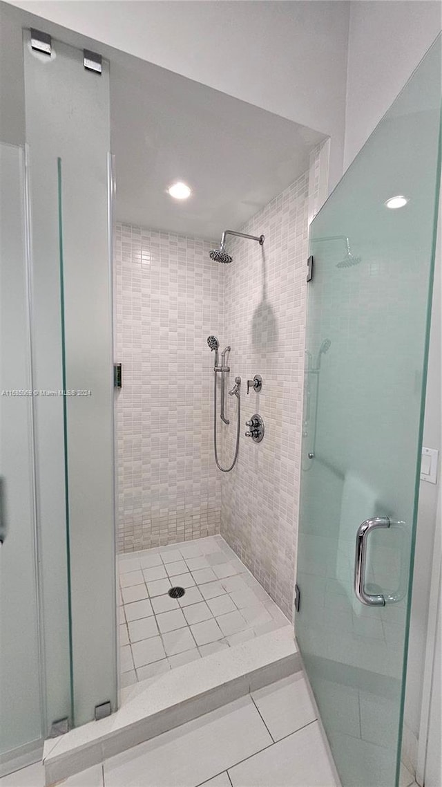 bathroom with a shower with shower door and tile patterned floors